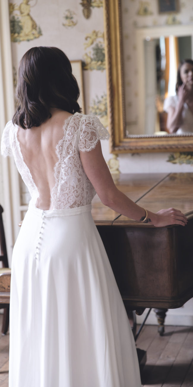 La robe de mariée Pénélope avec son dos nu bordé de dentelle est son décolleté cache coeur souligne la féminité de la future mariée avec élégance