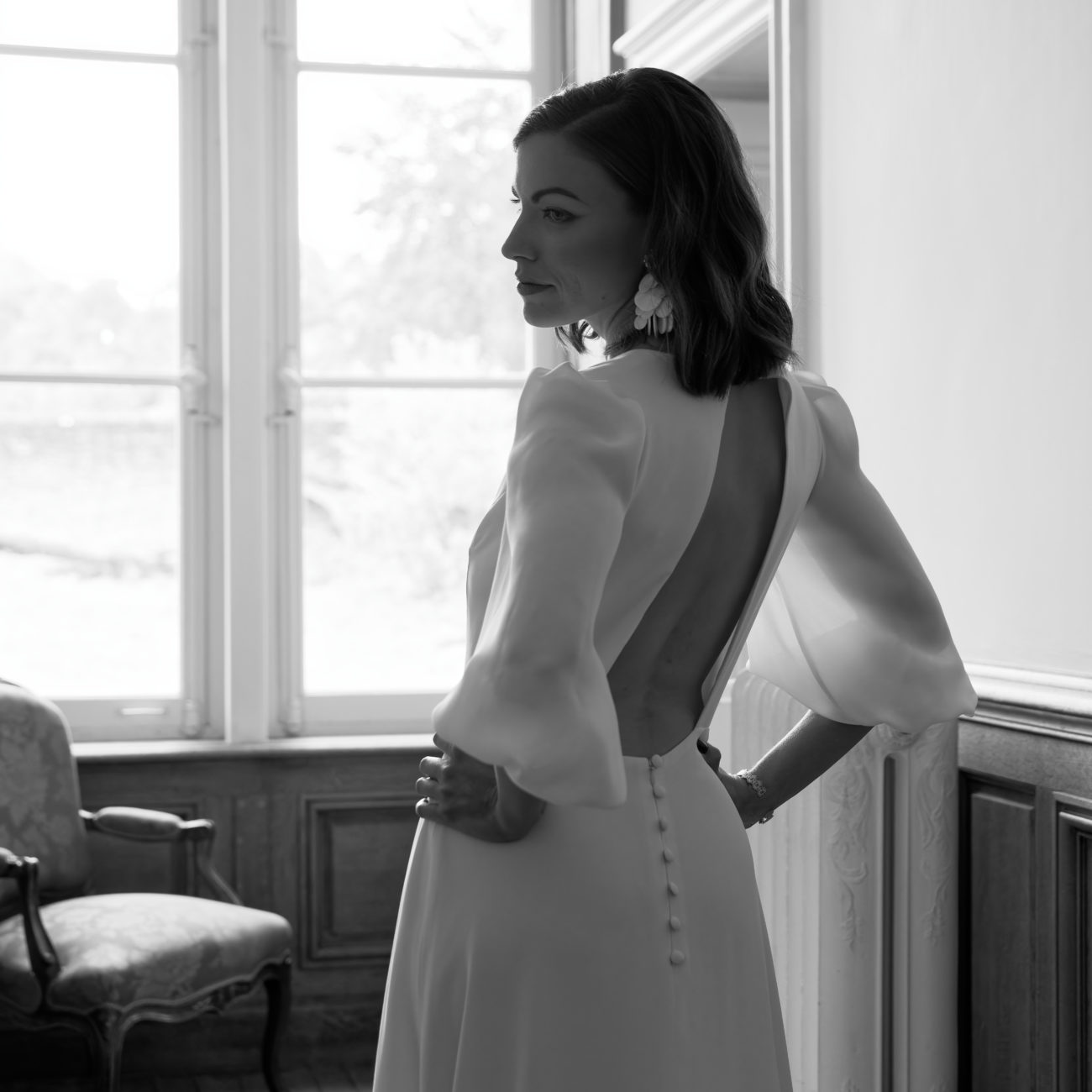 La robe de mariée Alba à traîne en dentelle, manches bouffantes et dos nu est une tenue couture raffinée et sensuelle pour la mariée moderne à la recherche d'élégance et féminité pour son mariage