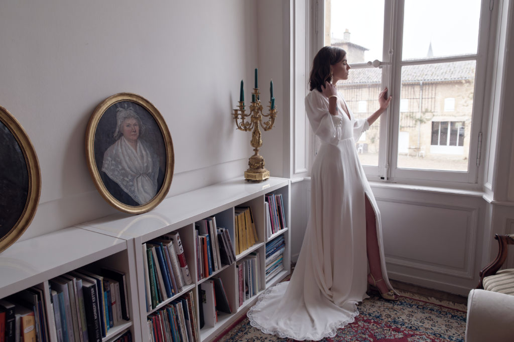 La robe de mariée Alba à traîne en dentelle, manches bouffantes et dos nu est une tenue couture raffinée et sensuelle pour la mariée moderne à la recherche d'élégance et féminité pour son mariage