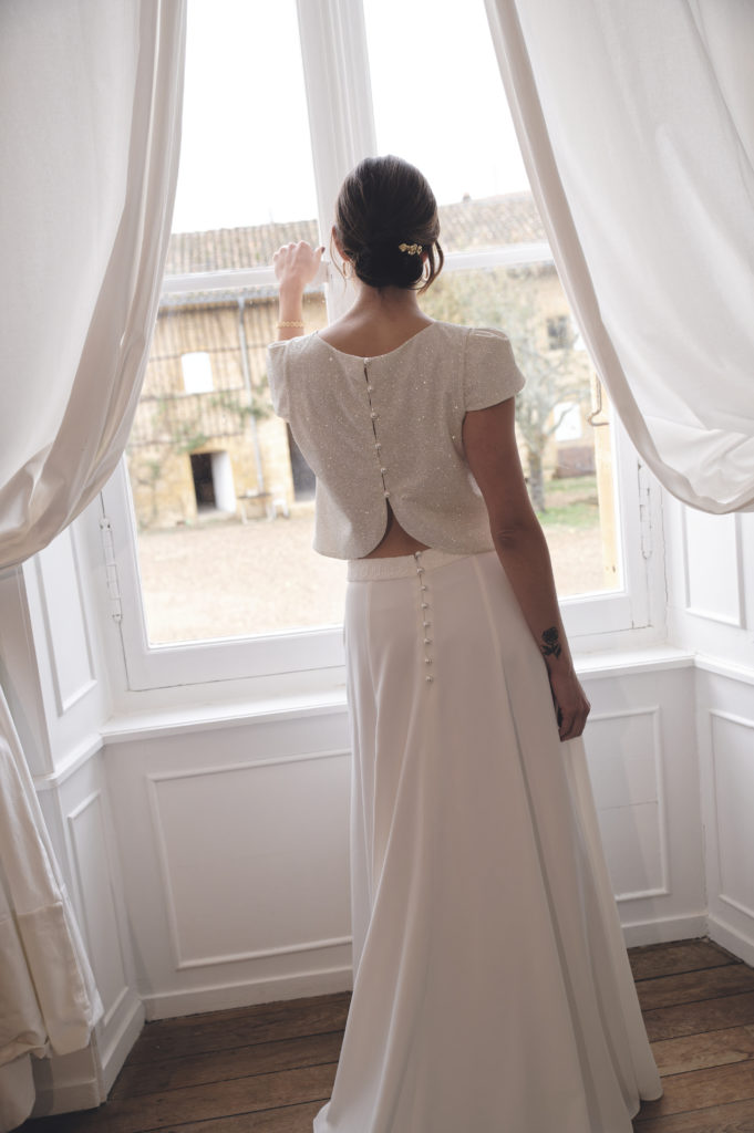 Une tenue de mariée minimaliste et raffinée avec ce top à paillettes et perles associé à une sculpturale jupe longue à traîne qui élance la silhouette